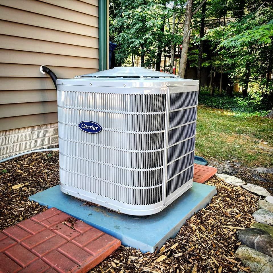 A carrier air conditioner is sitting outside of a house