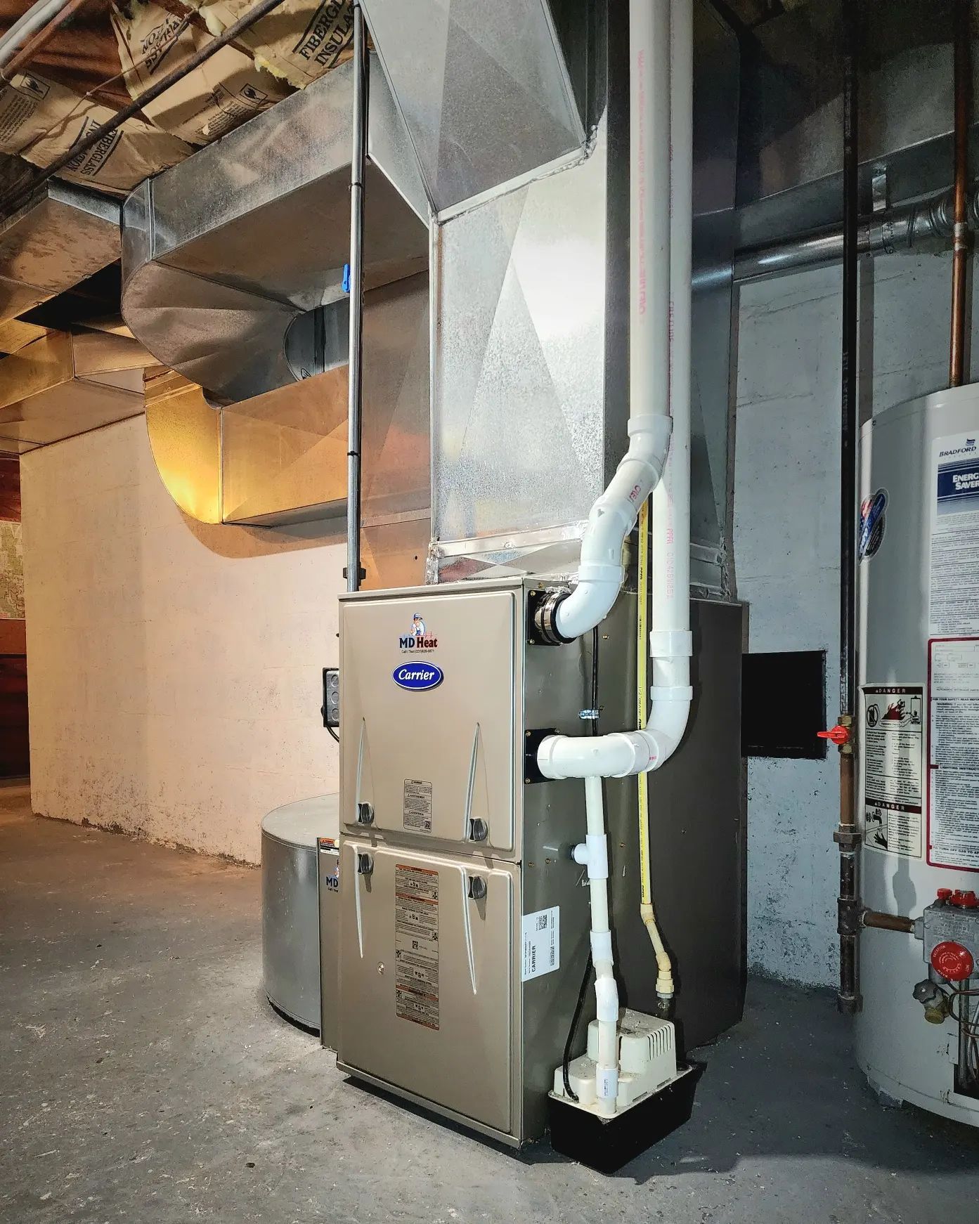A gas heater is sitting in a basement next to a water heater.