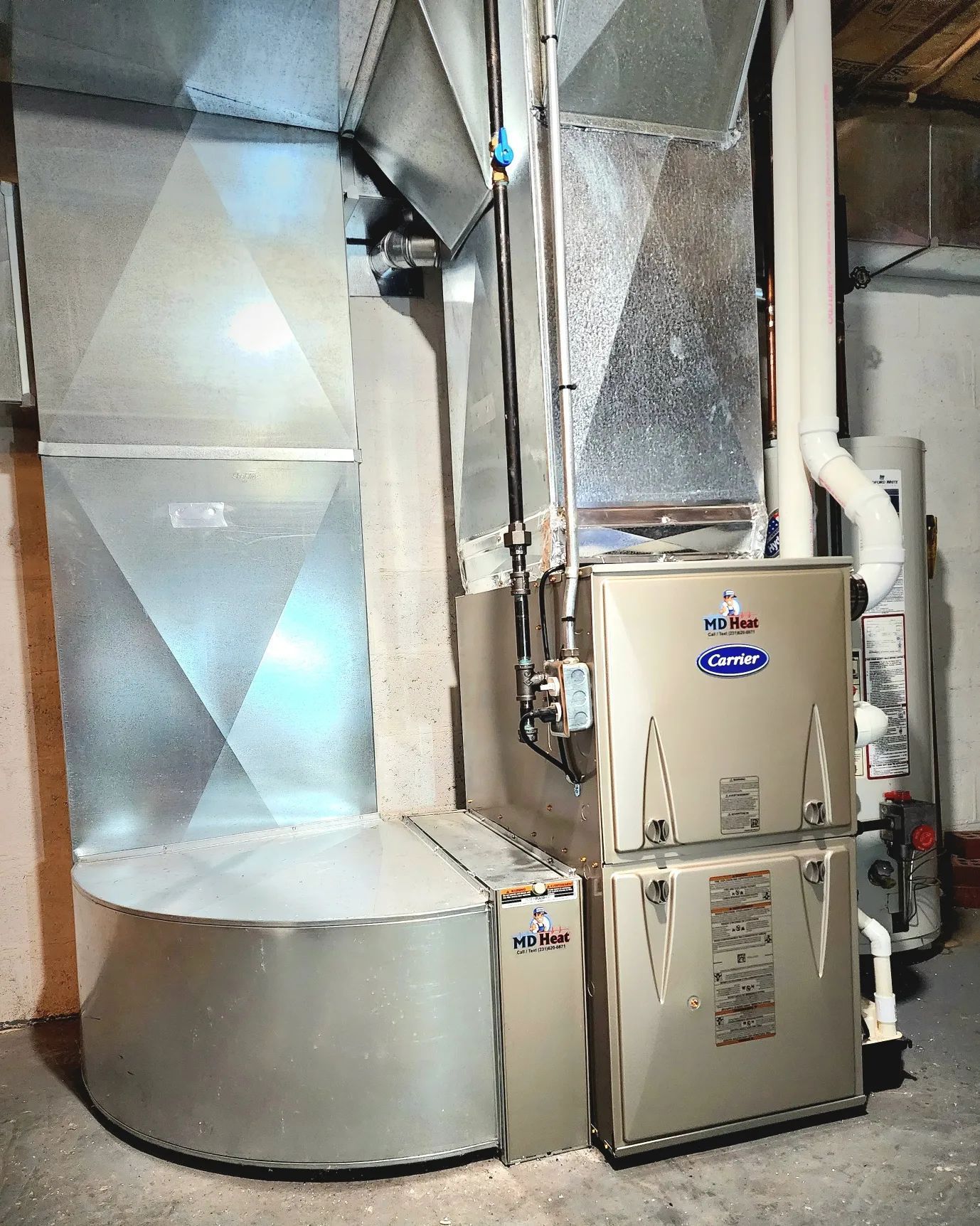 A furnace is sitting in a basement next to a duct.