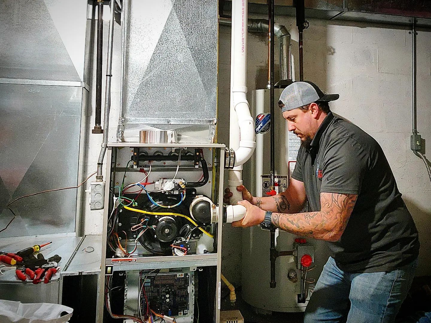 A man is working on a heating system in a basement.