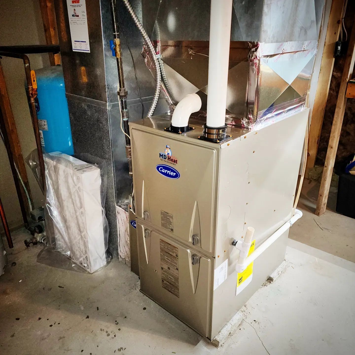 A carrier furnace is sitting in a basement next to a water tank.