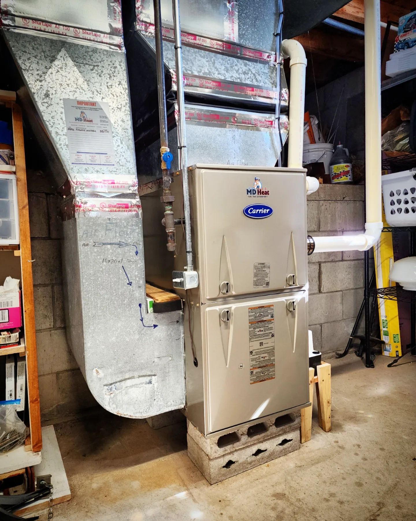 A carrier furnace is sitting in a basement next to a water heater