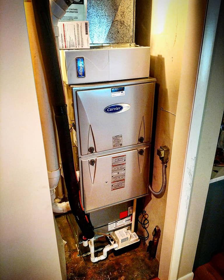 A carrier air conditioner is sitting in a corner of a room.