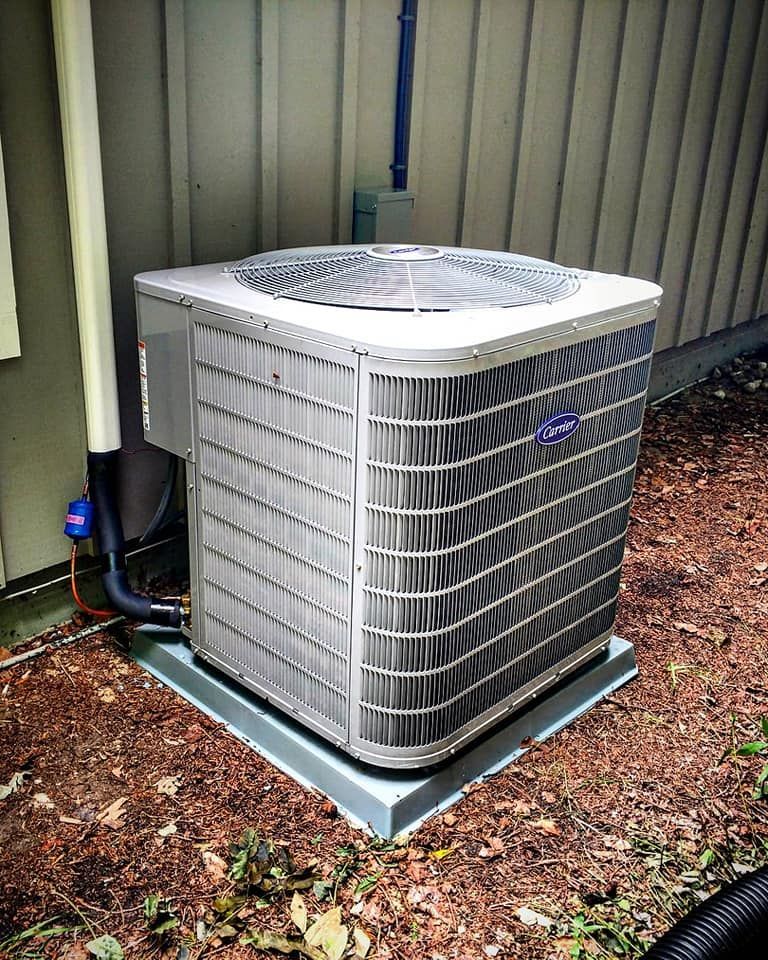 A carrier air conditioner is sitting outside of a house.