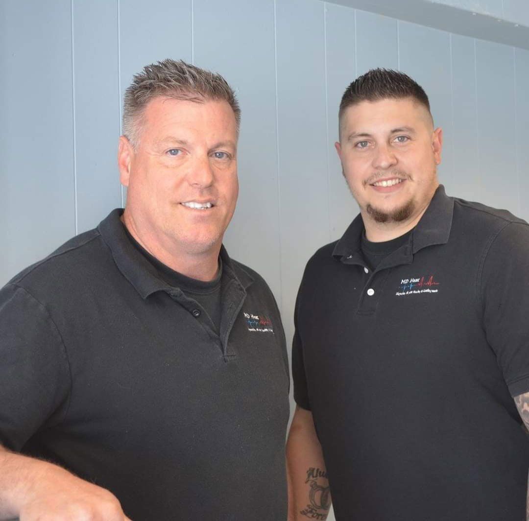 Two men are posing for a picture and one has a tattoo on his arm