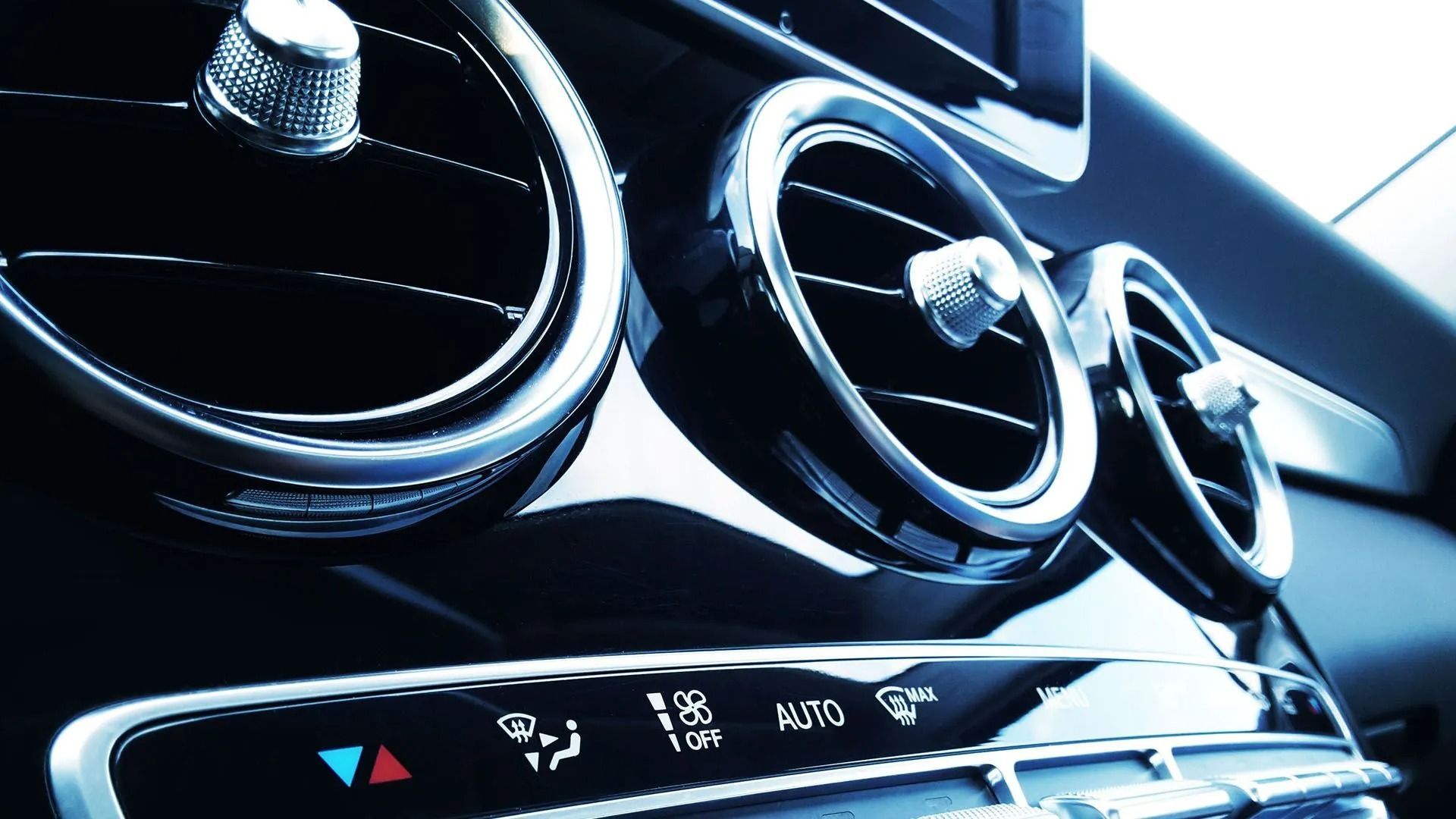 Interior car dashboard with chrome air vents and climate control buttons.