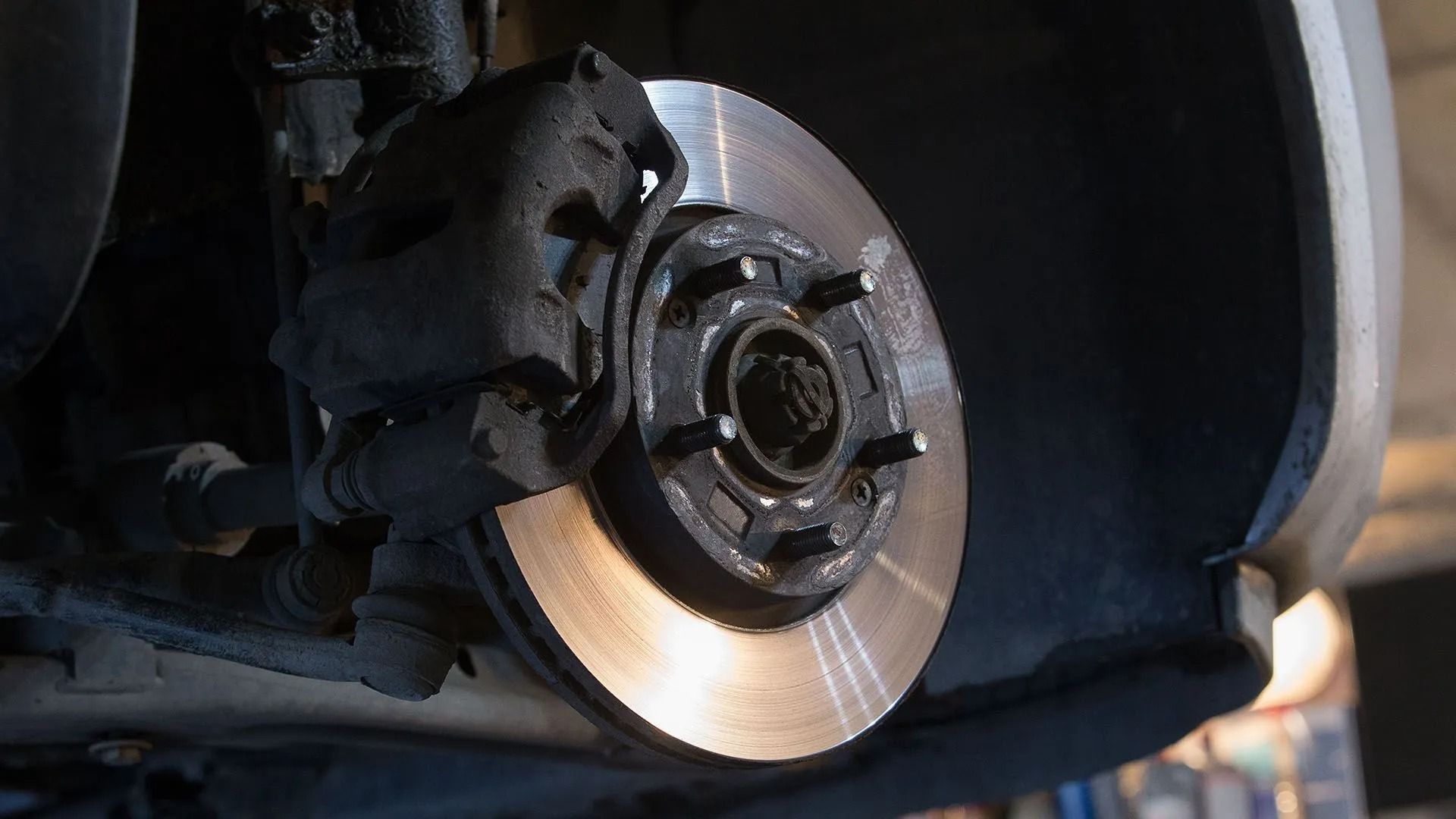 Car's brake disc and caliper; shows a close-up of the metal components, with wear and tear visible.