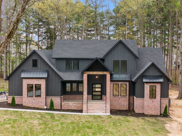 A large house with a black roof is surrounded by trees.