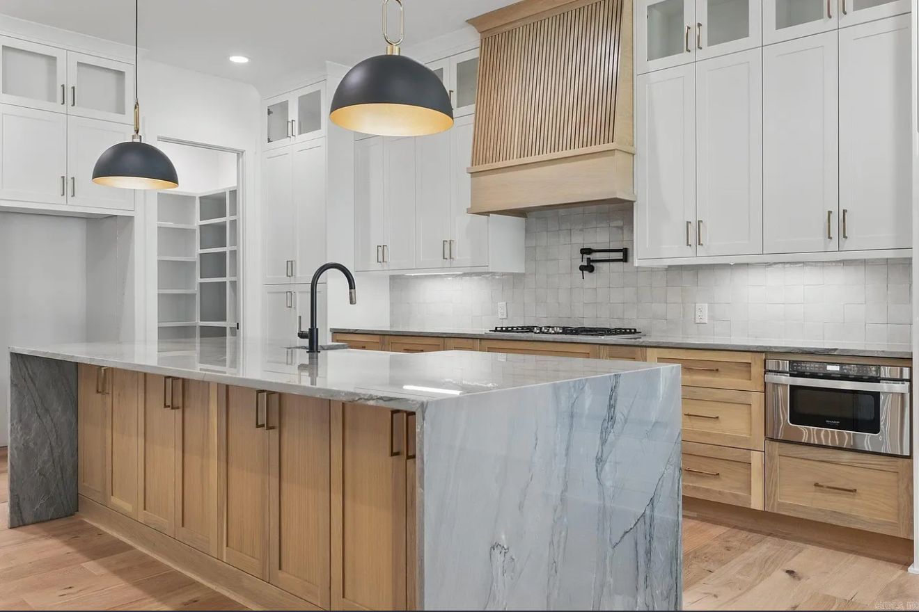 A kitchen with white cabinets and a large island in the middle.