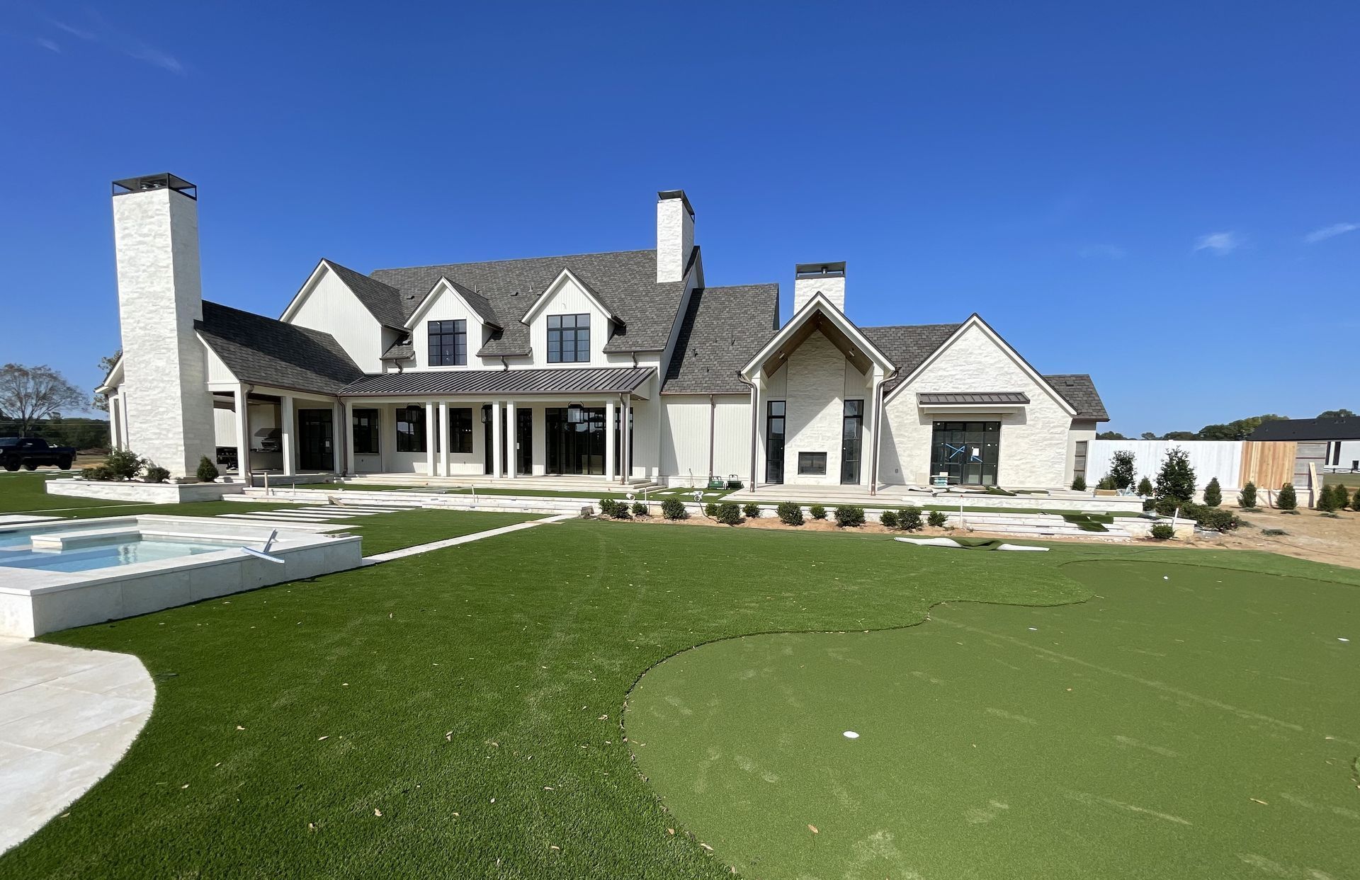 A large white house with a putting green in front of it.
