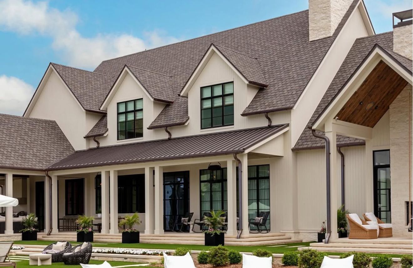 A large white house with a brown roof and a large porch