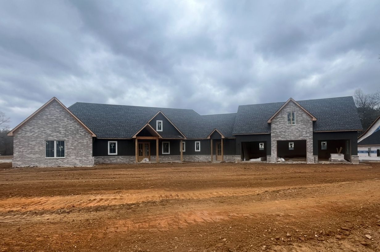 A large house is being built in a dirt field.
