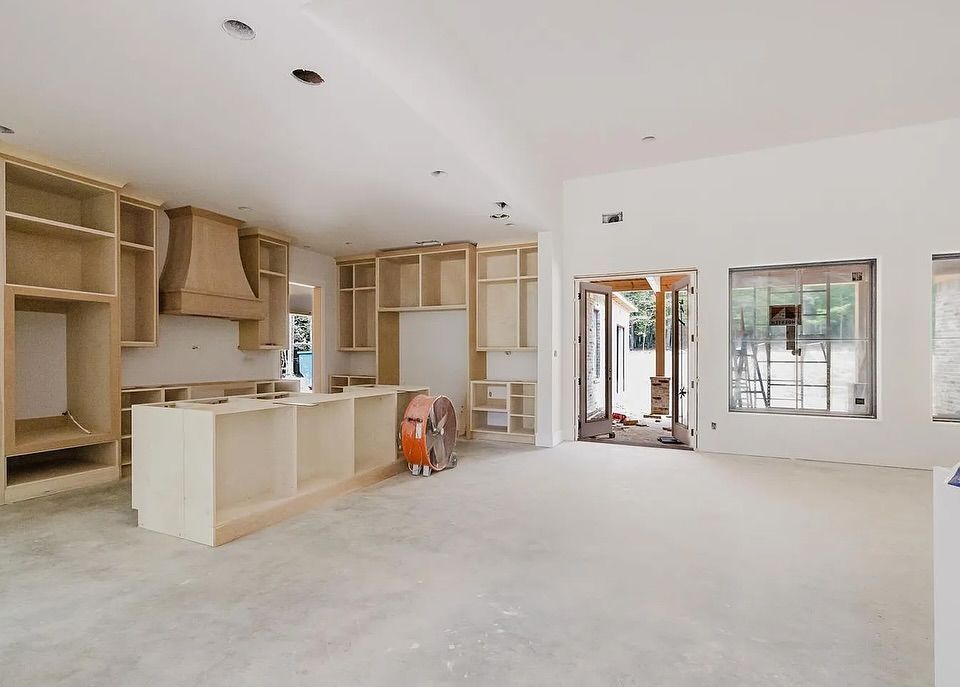 A kitchen in progress with unfinished cabinets, bare walls, and concrete floors.