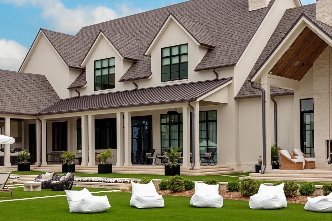 A large white house with a brown roof and a large porch