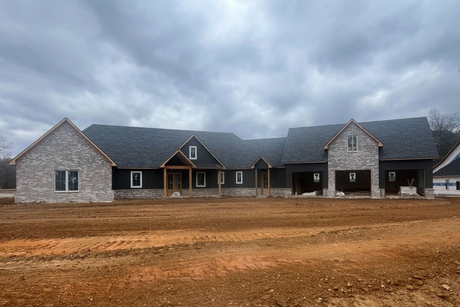 A large house is being built in a dirt field.