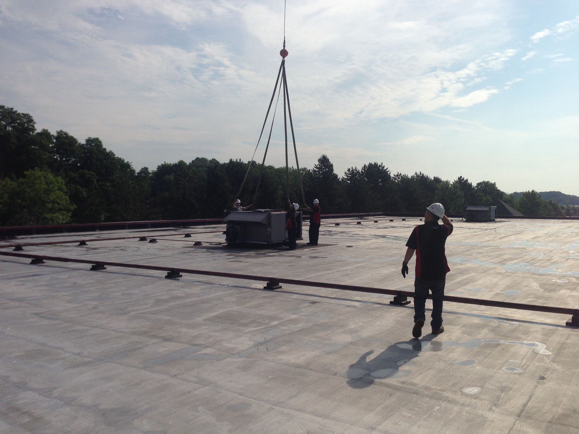 A man standing on top of a roof with a crane in the background