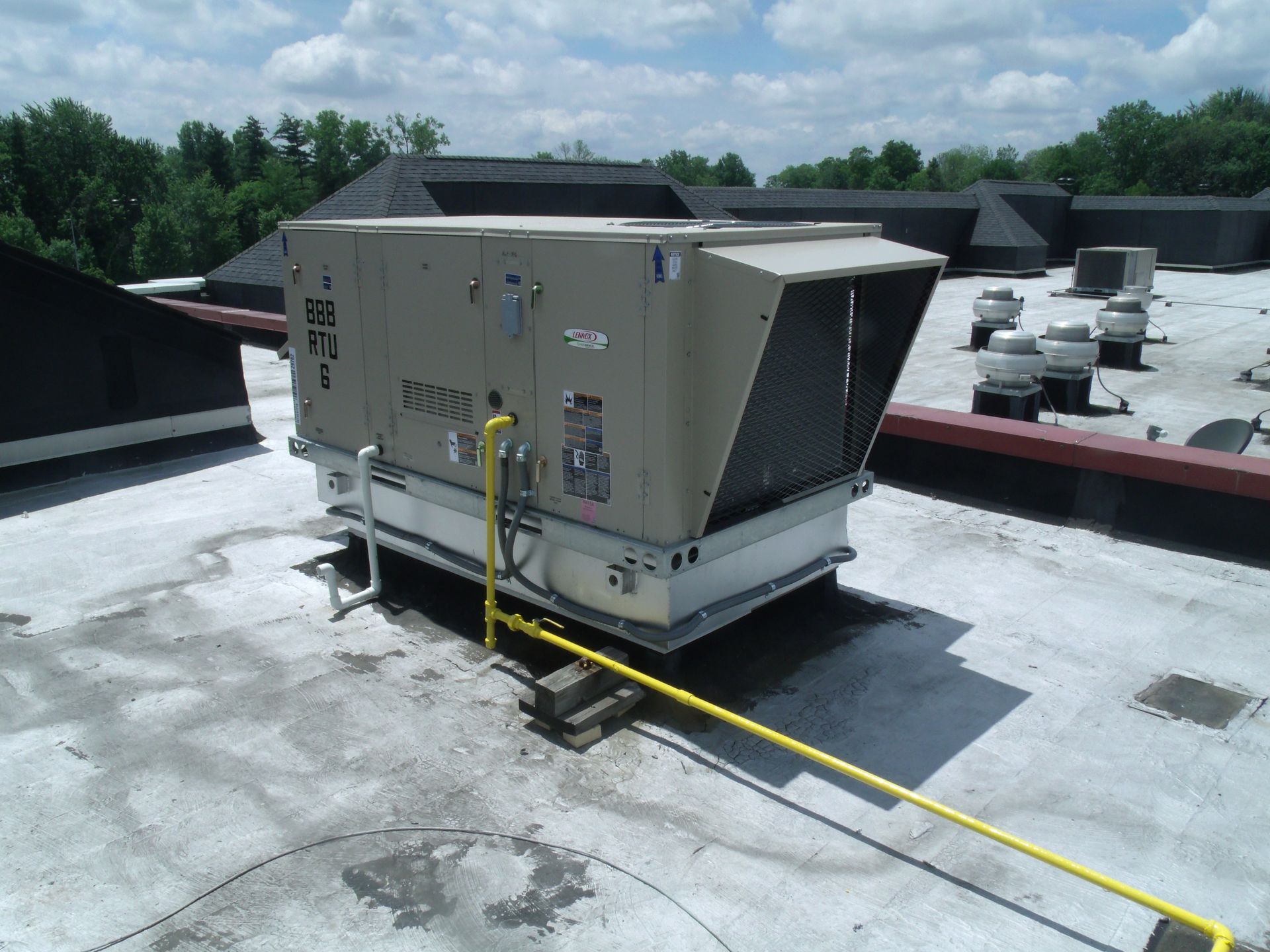 A large unit on top of a roof with a yellow pipe attached to it