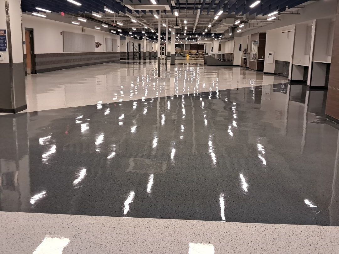 Empty indoor hallway with a glossy reflective floor and overhead lights