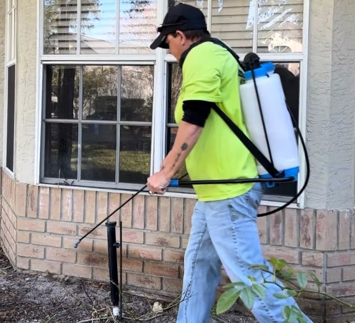a person spraying insecticide near a window with a backpack sprayer