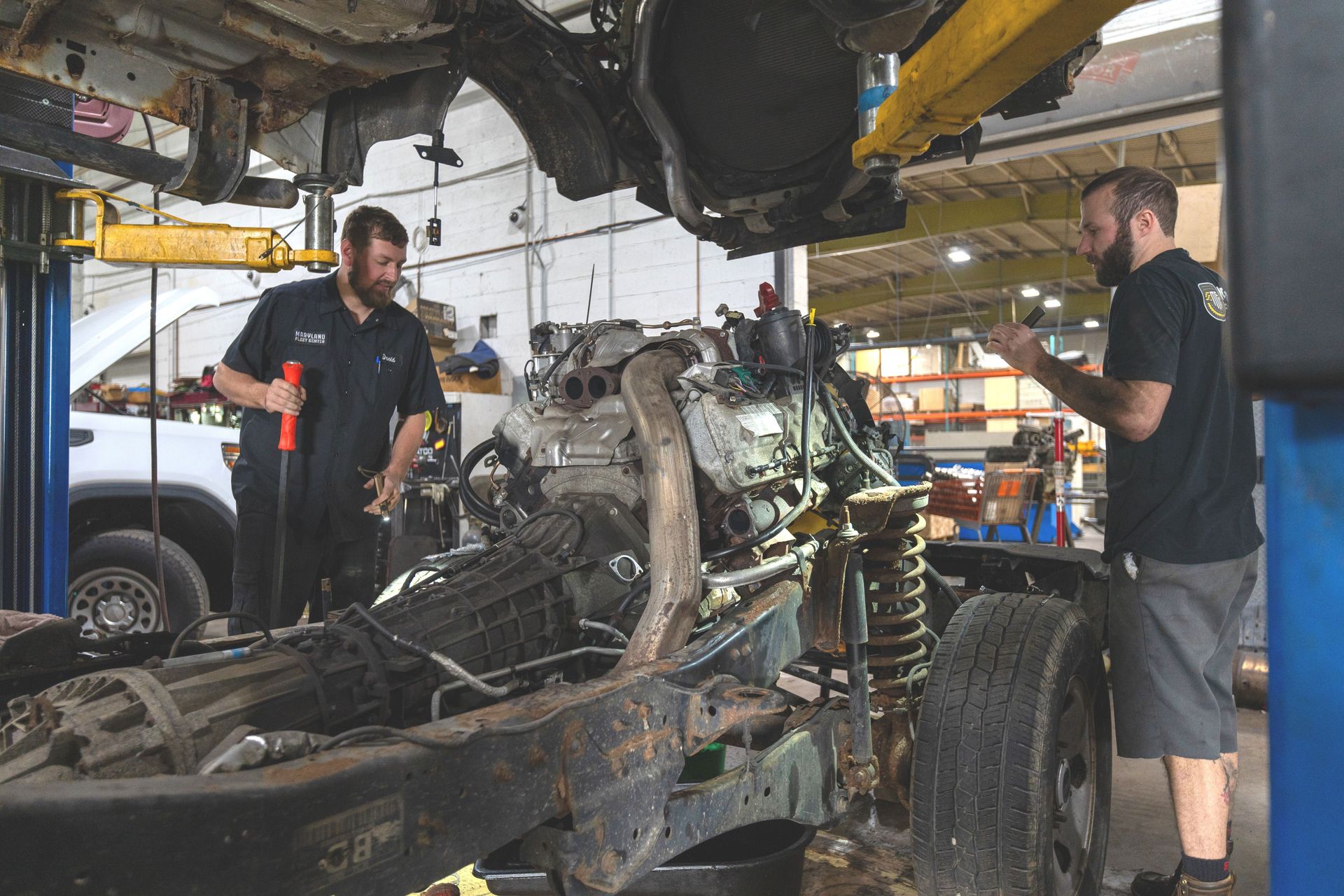 A man is working on the engine of a truck in a garage.