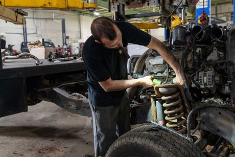 A man is working on the engine of a truck in a garage.