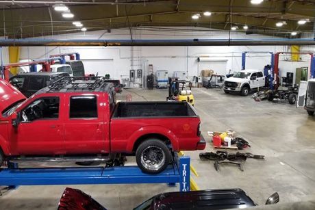 A red truck is sitting on top of a blue lift in a garage