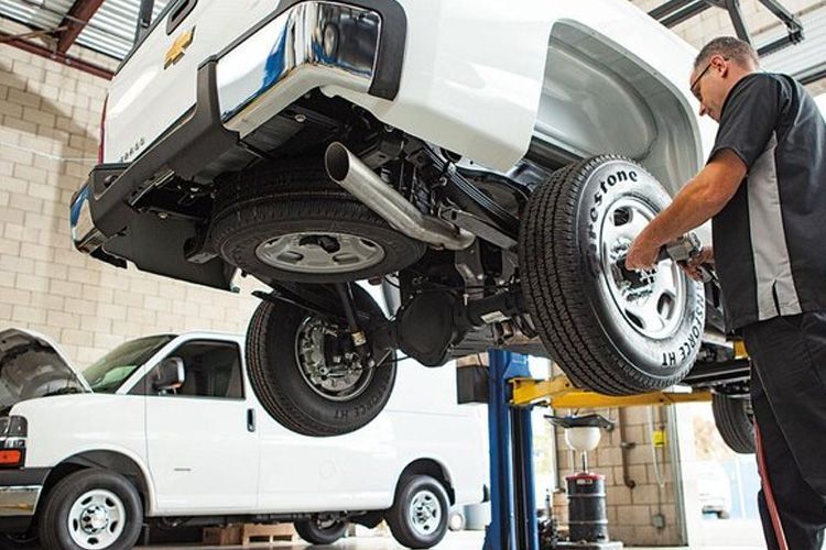 A man is working on a truck on a lift in a garage.