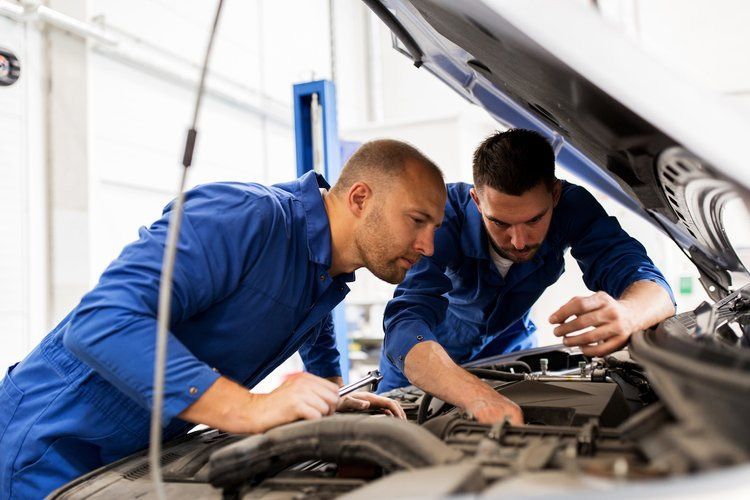 Two mechanics are working on a car in a garage.