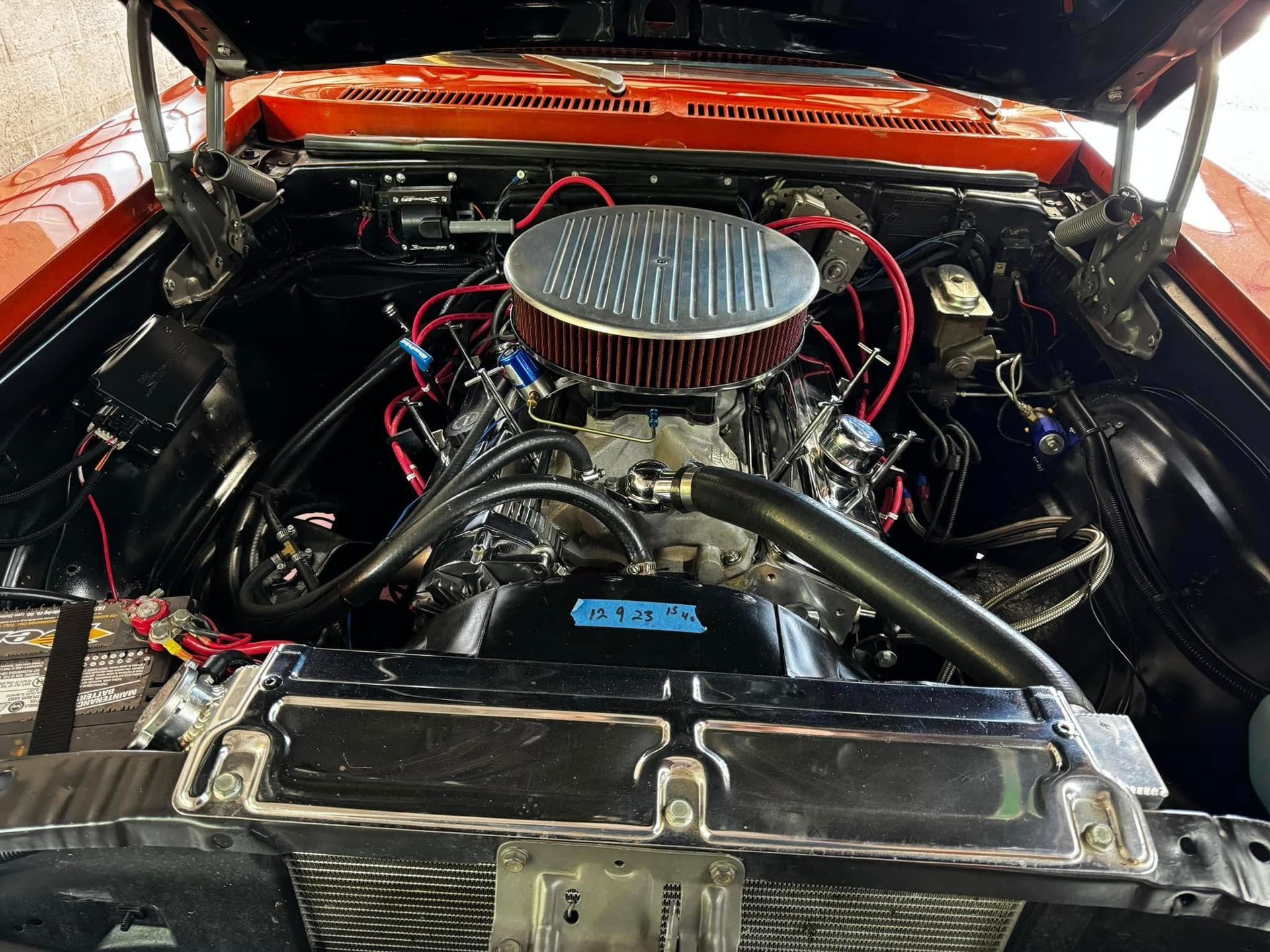 Red car engine with chrome details and air filter.