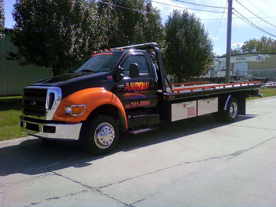 Black and orange tow truck parked on a paved road. It has