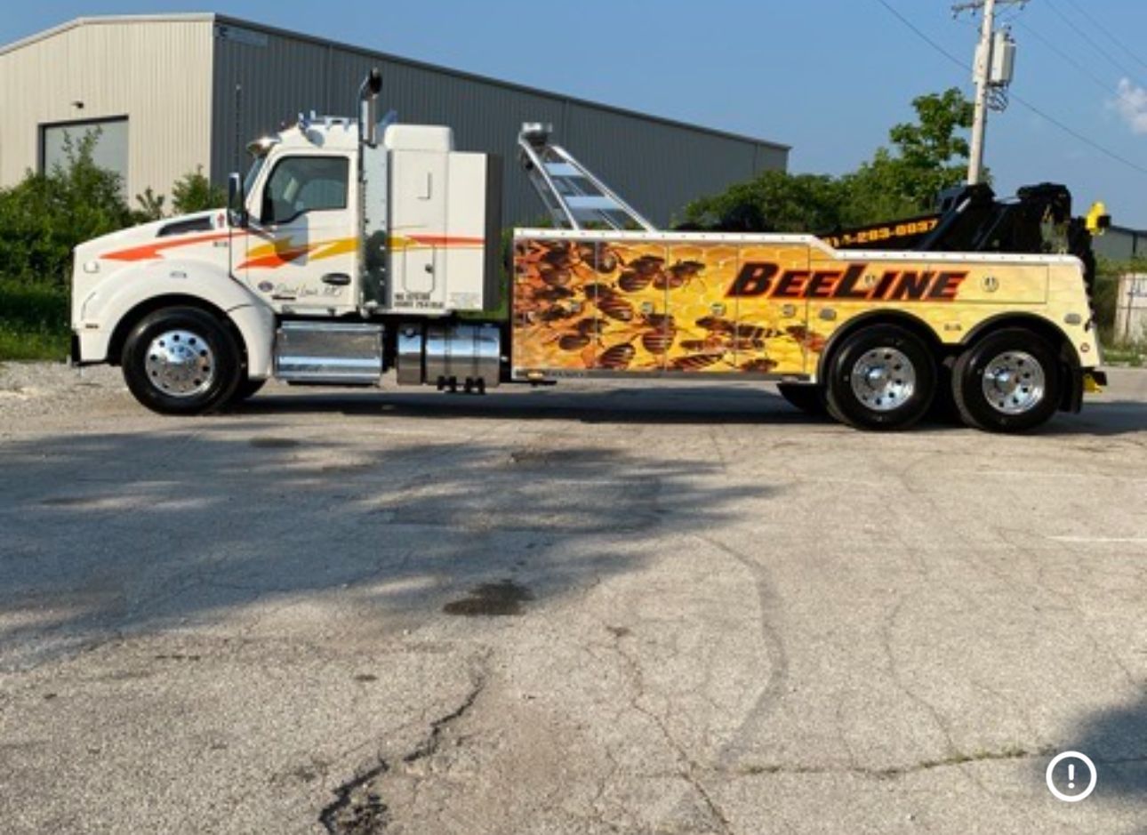 A beeline tow truck is parked in a parking lot