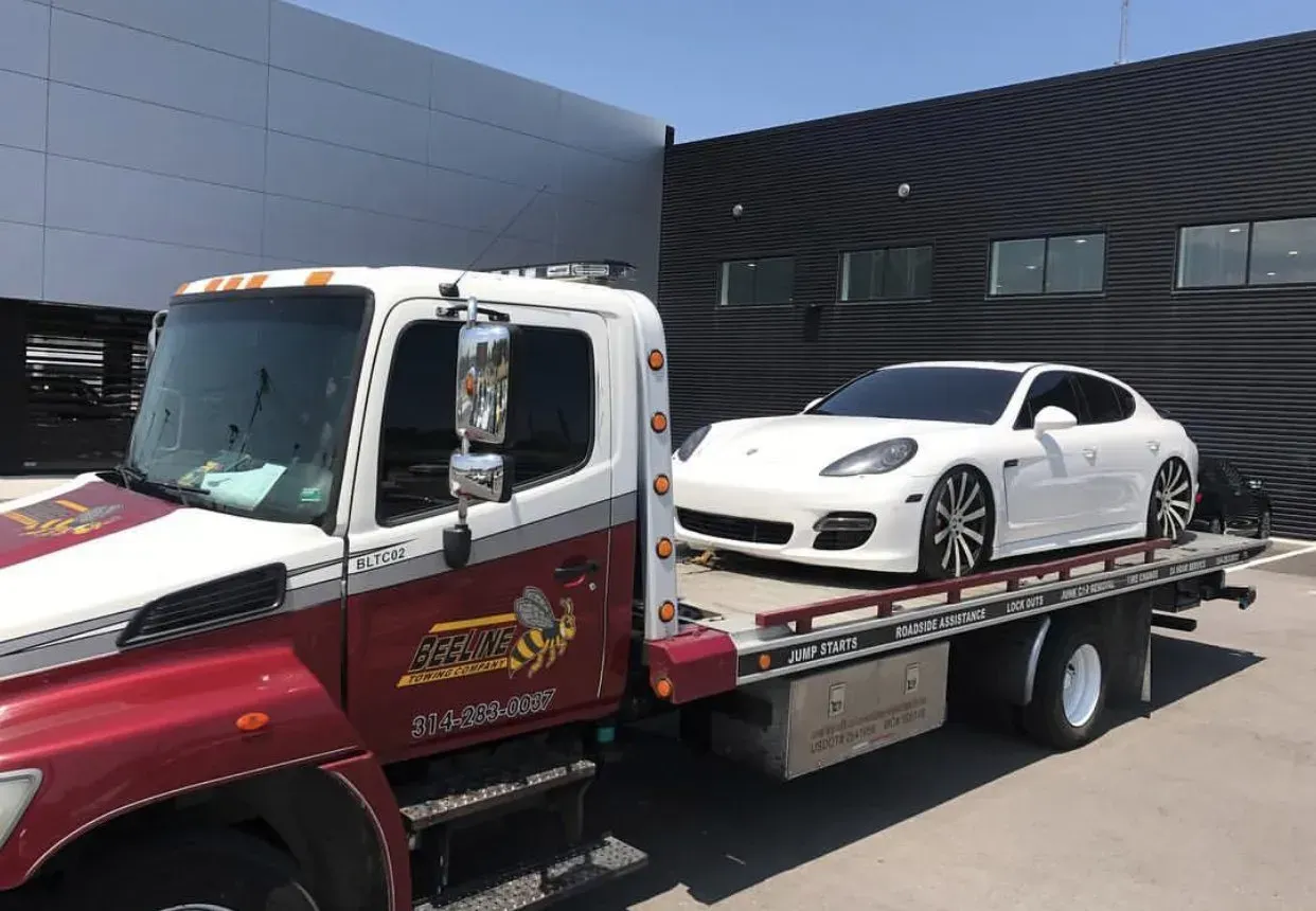A white car is being towed by a tow truck.