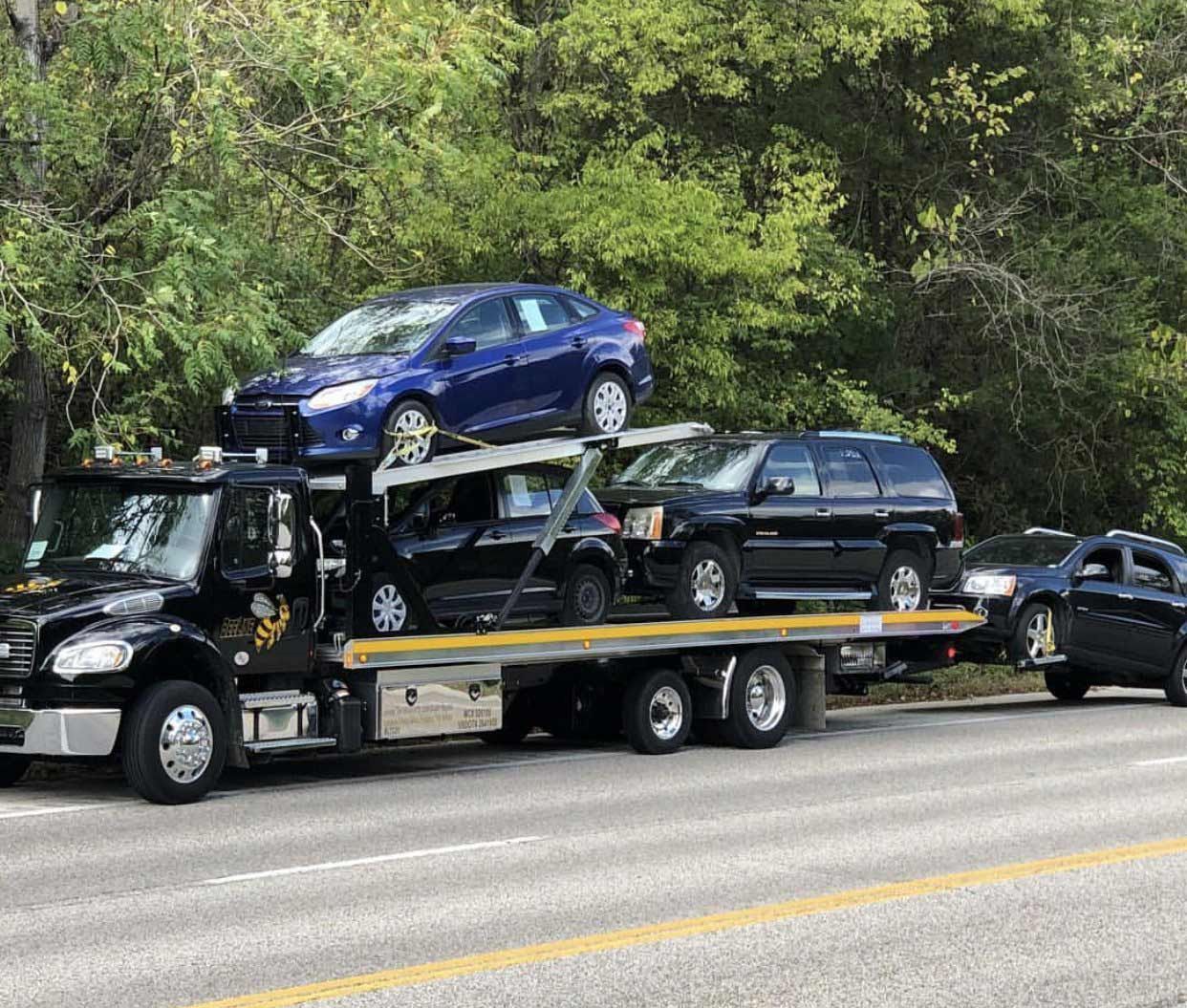 A tow truck is carrying a bunch of cars down the road.