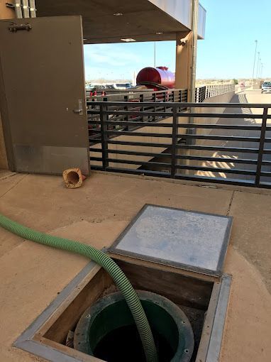 A green hose is coming out of a hole in the ground.