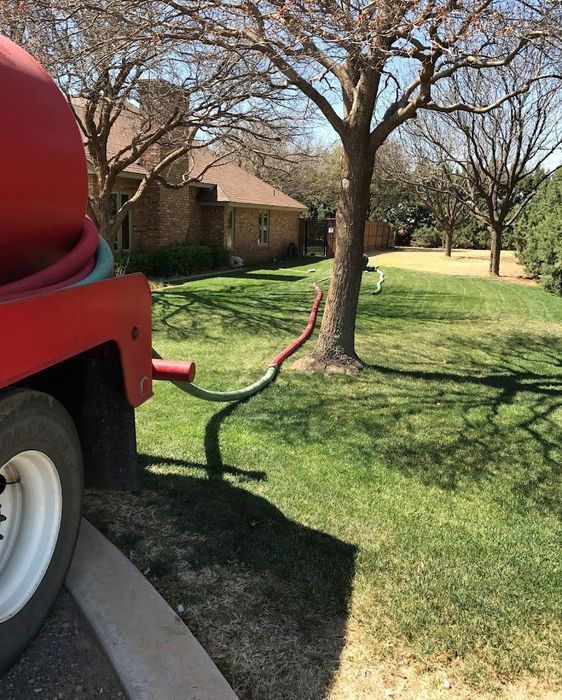 A red truck with a hose attached to it is parked in front of a house.