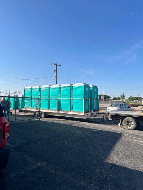 A truck is towing a trailer full of portable toilets.