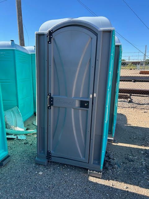 A portable toilet is sitting on the ground in a parking lot