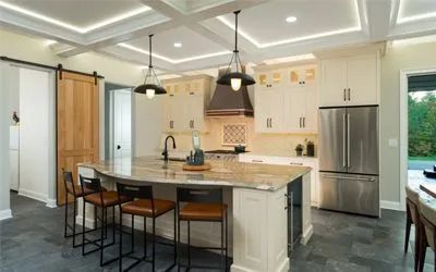 A kitchen with white cabinets, stainless steel appliances, a large island, and a sliding barn door.