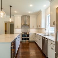 A kitchen with white cabinets , stainless steel appliances , and hardwood floors.