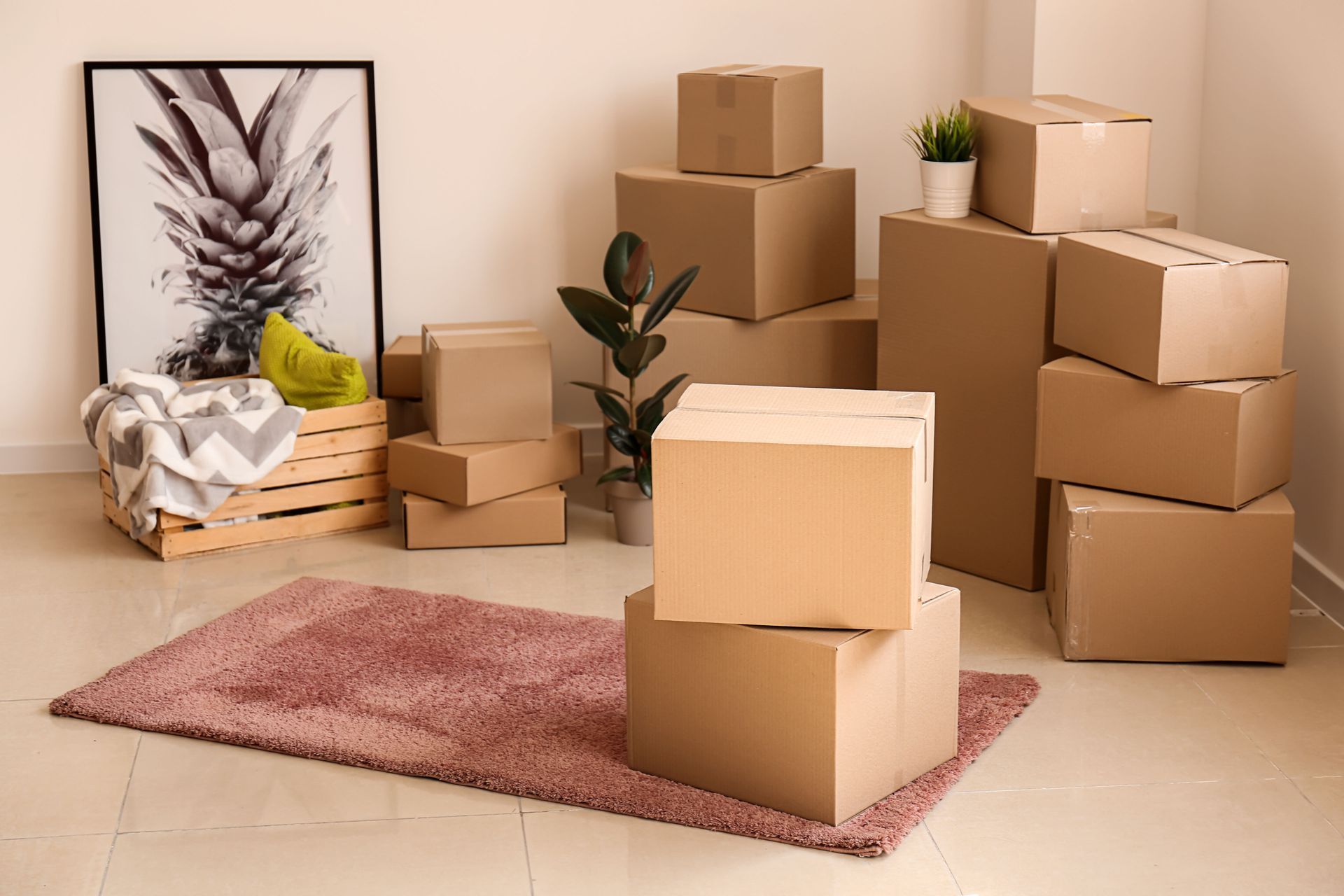 Packed cardboard moving boxes in a beige room with a pink rug and framed wall art