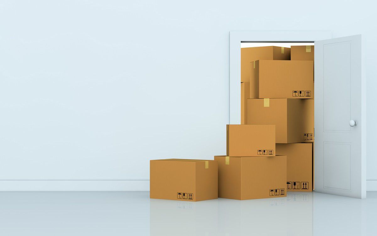Cardboard moving boxes stacked in a doorway of a sparse empty room