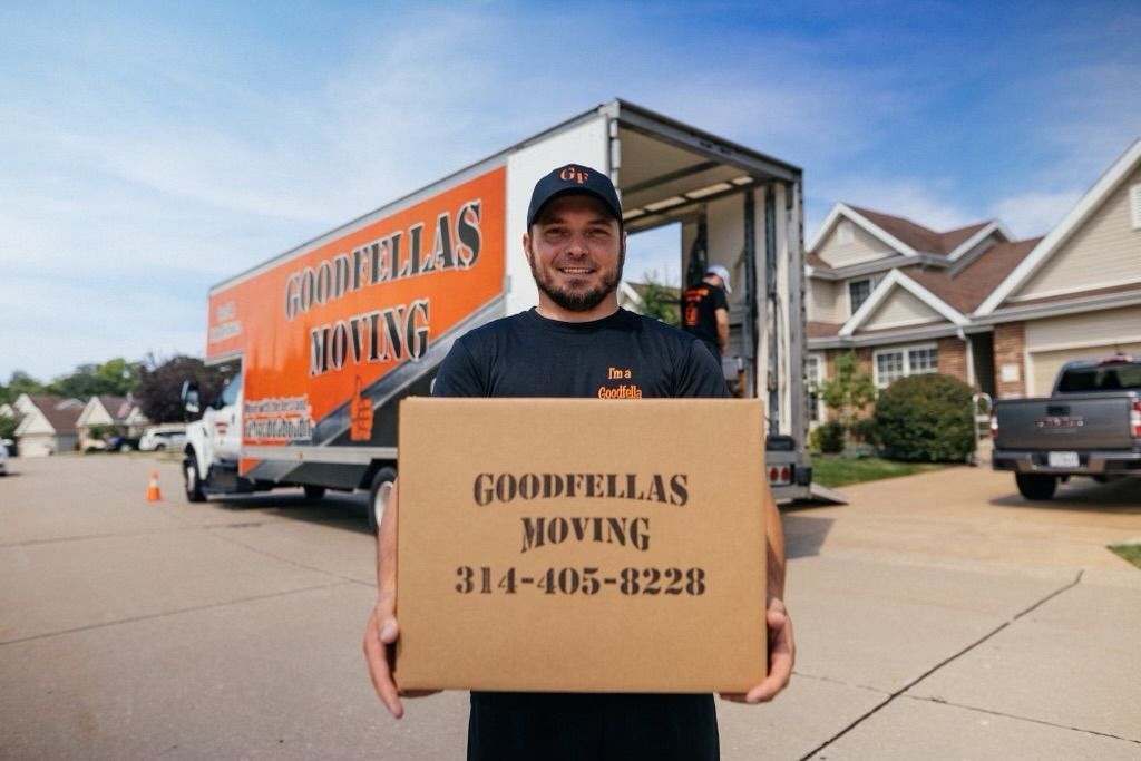 Goodvillas Moving worker holding company sign in front of an orange moving truck on a suburban street