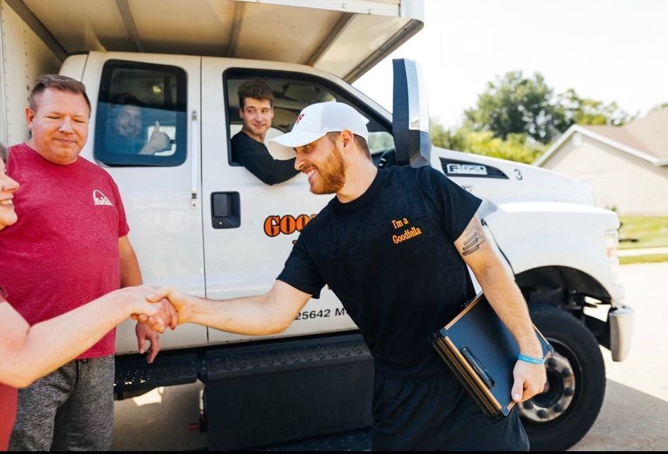 People shaking hands beside a white truck, with one man standing in the open cab door.