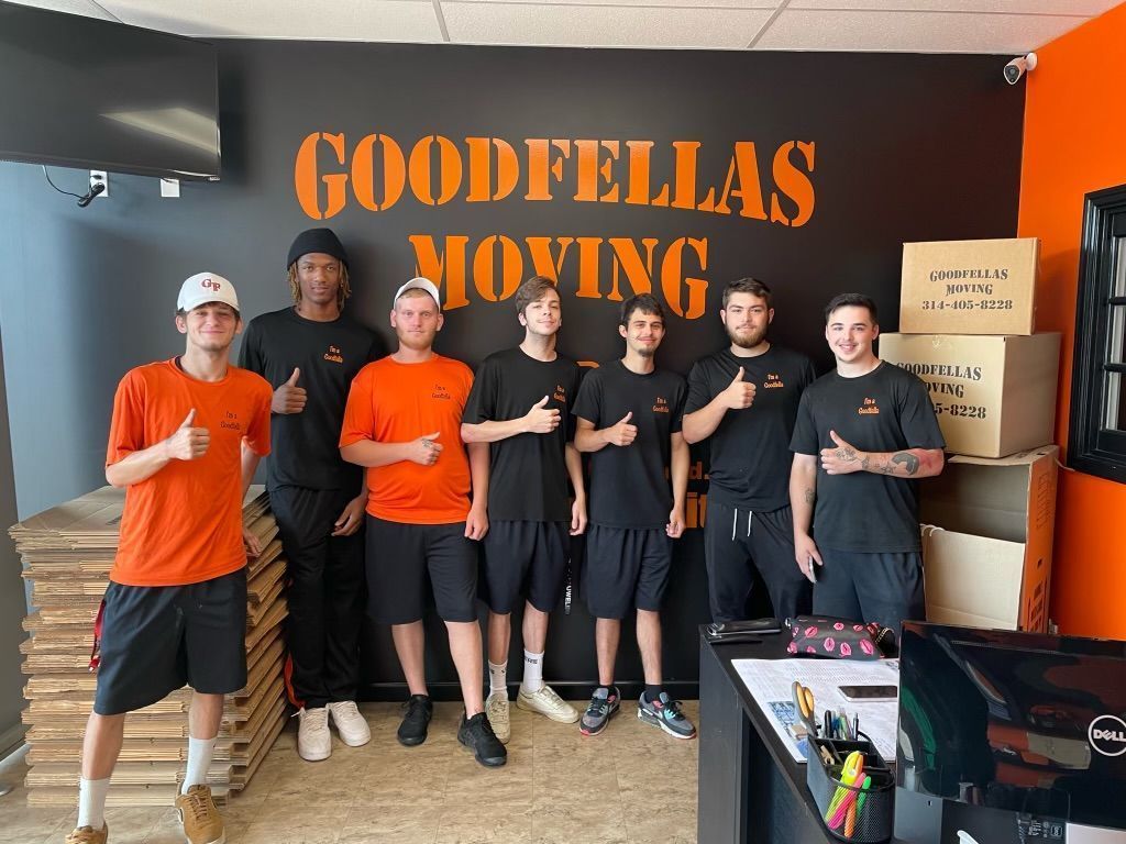 Goodfellas Moving team posing in orange and black uniforms inside a moving office