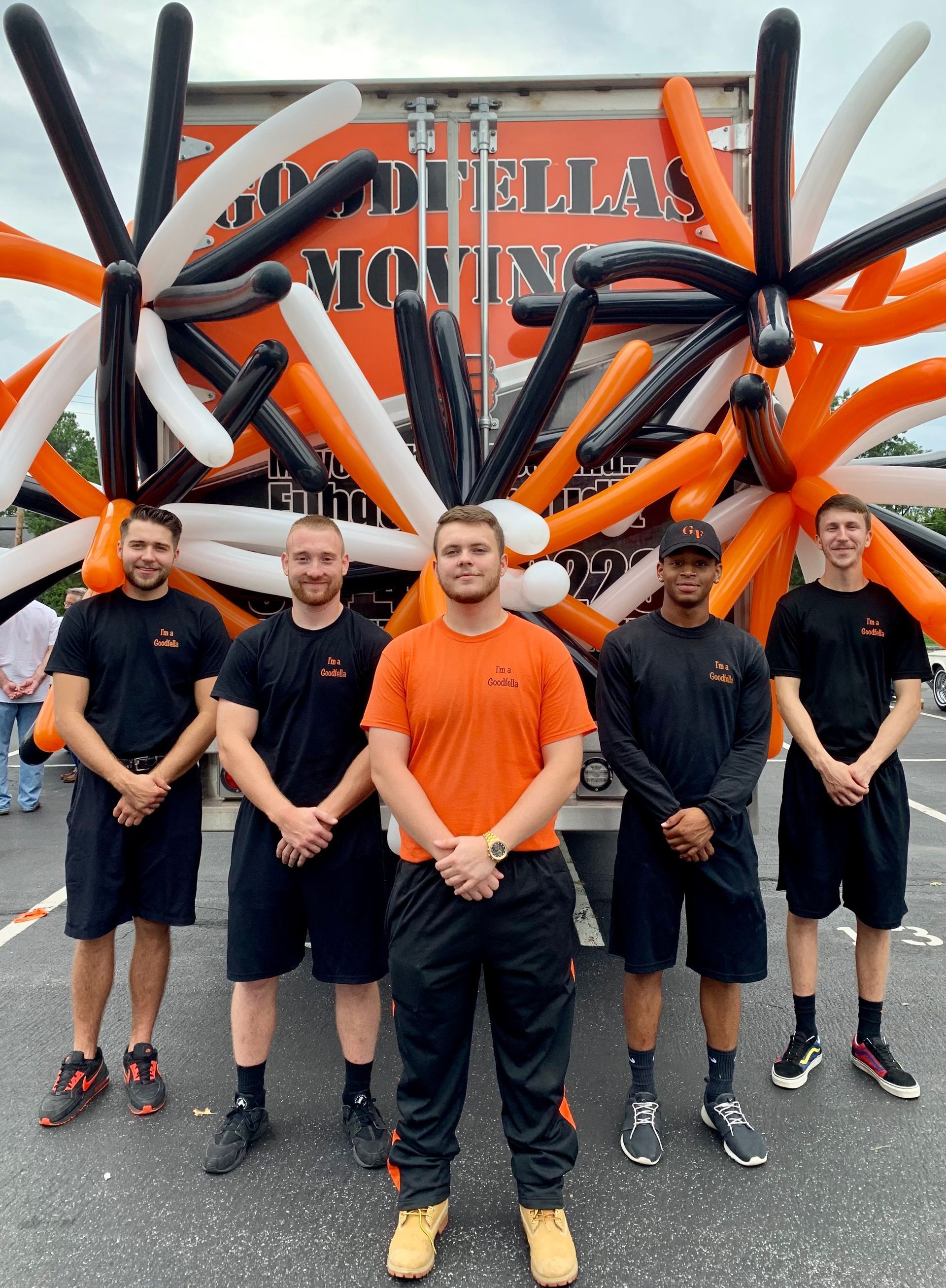 Five runners posing in front of a black and orange obstacle course structure outdoors