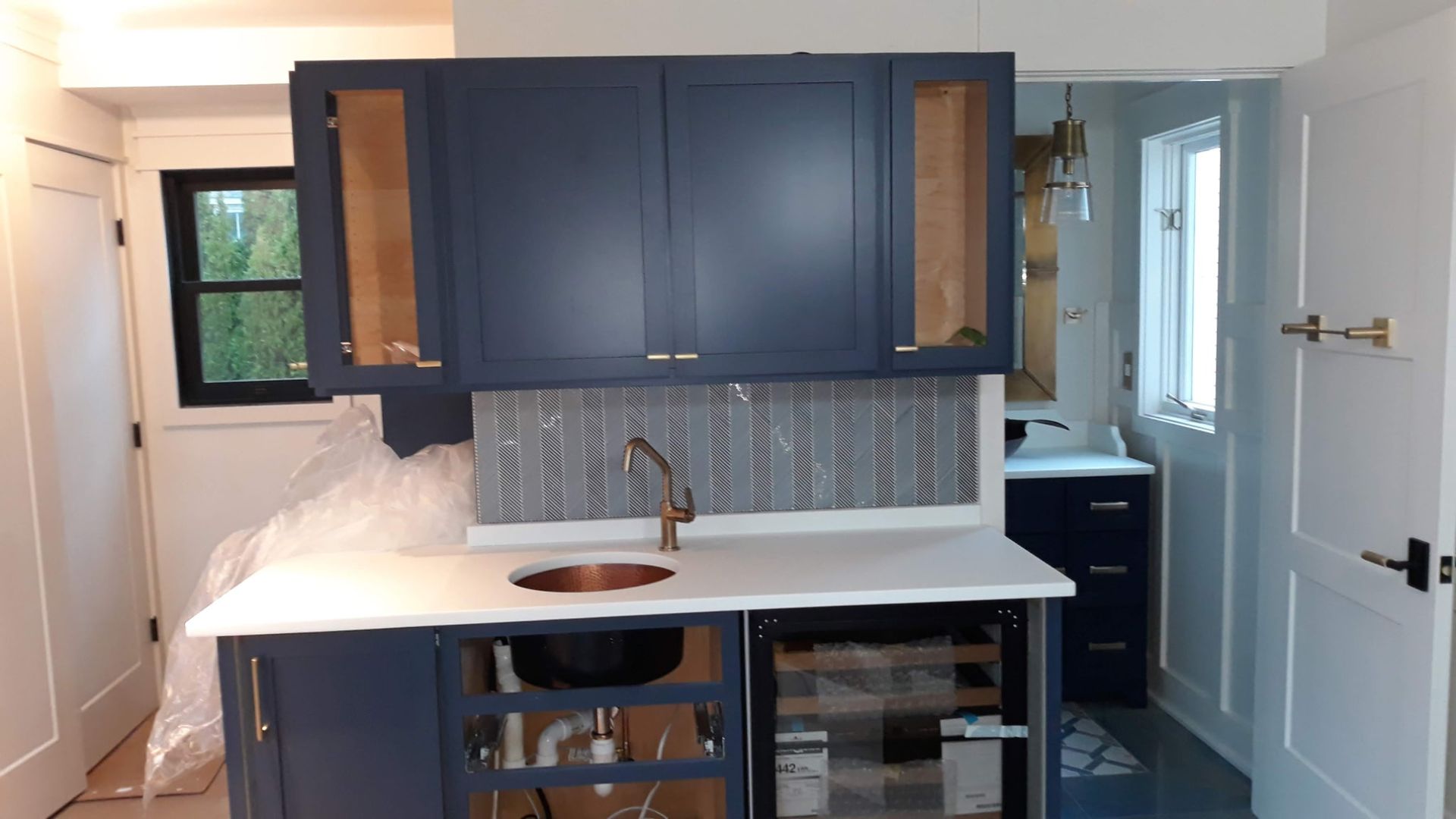Navy blue cabinets and countertop with copper faucet in small room renovation.
