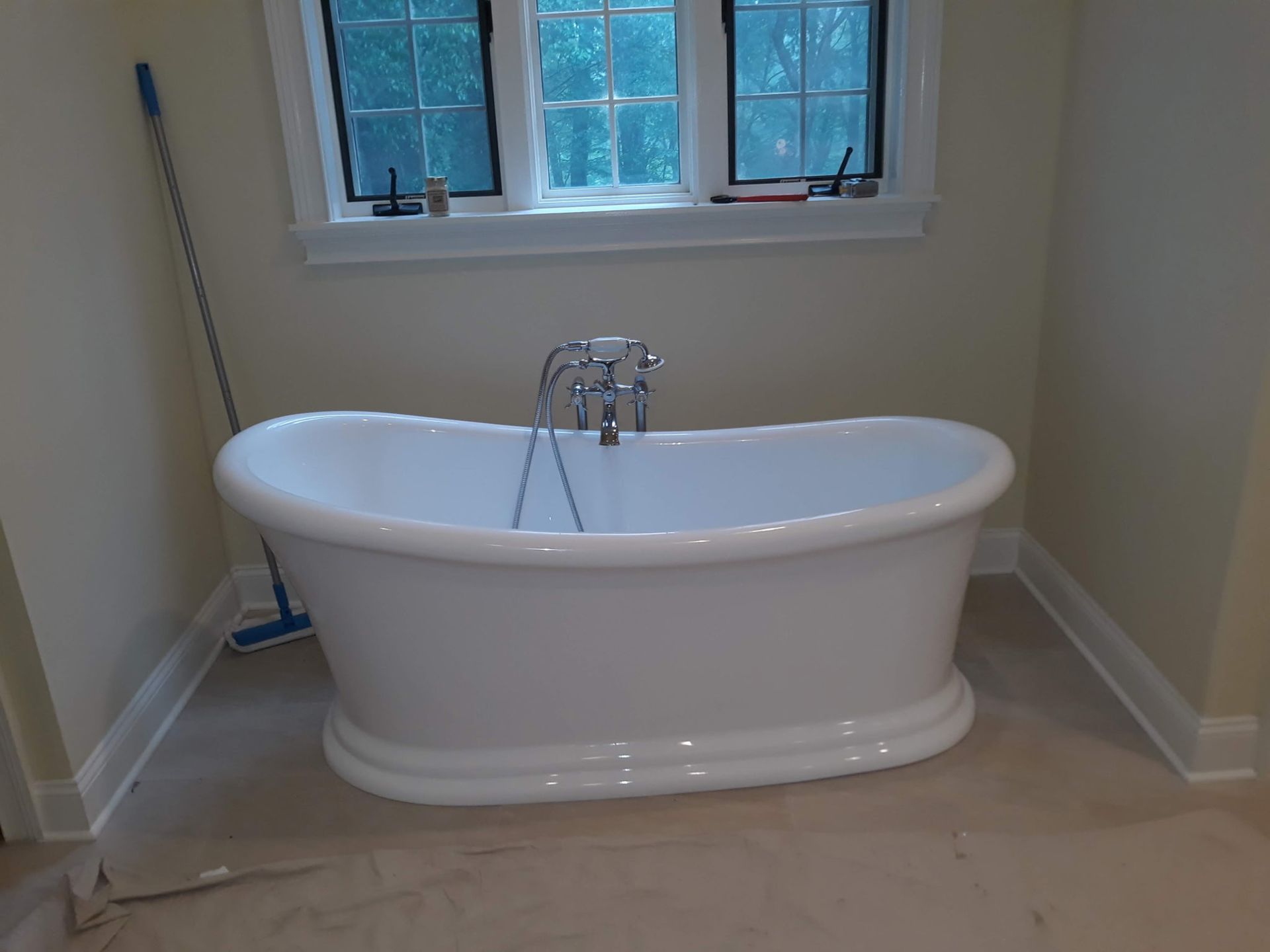 White freestanding bathtub in a bathroom, under a window with a view.