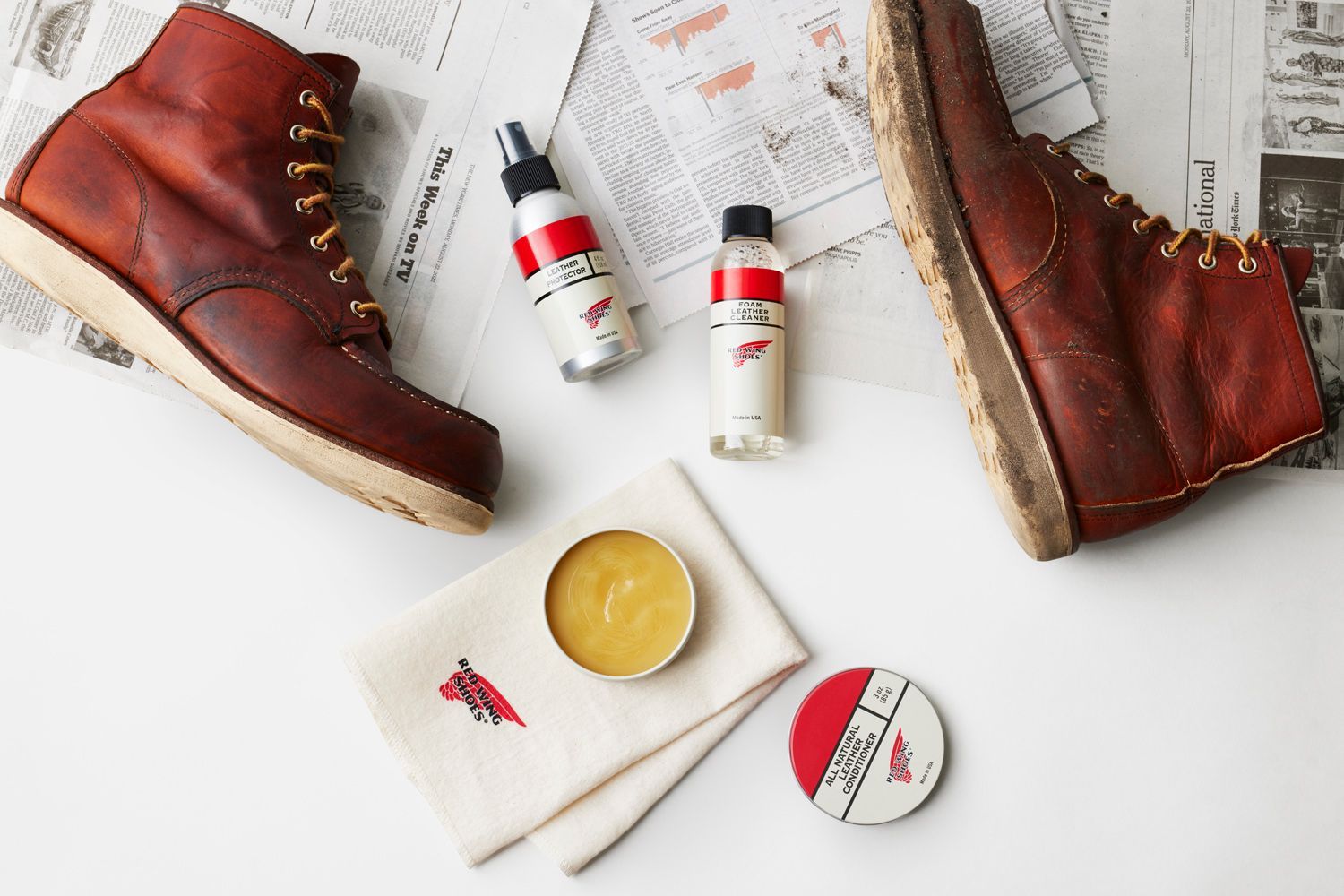 Red Wing boots with leather care products on newspaper.