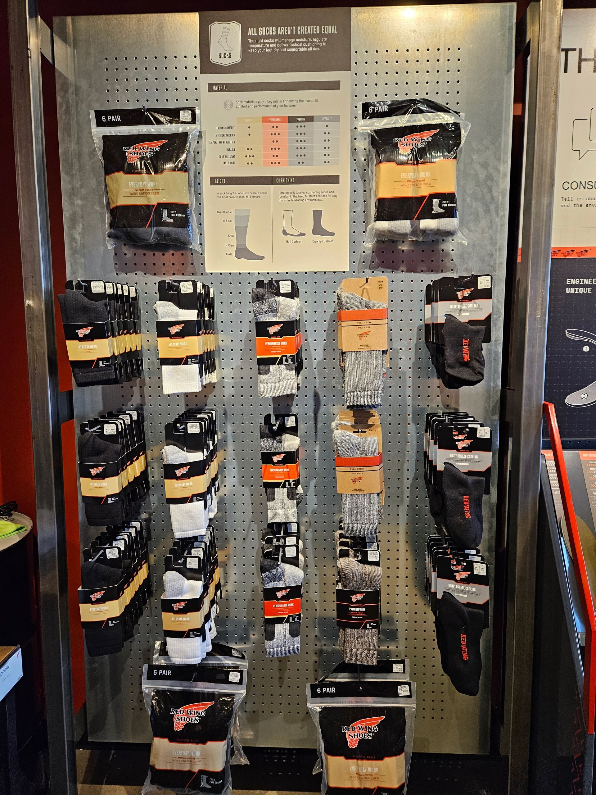 Socks display on a store rack, various styles in black, yellow, and white, with size charts posted.