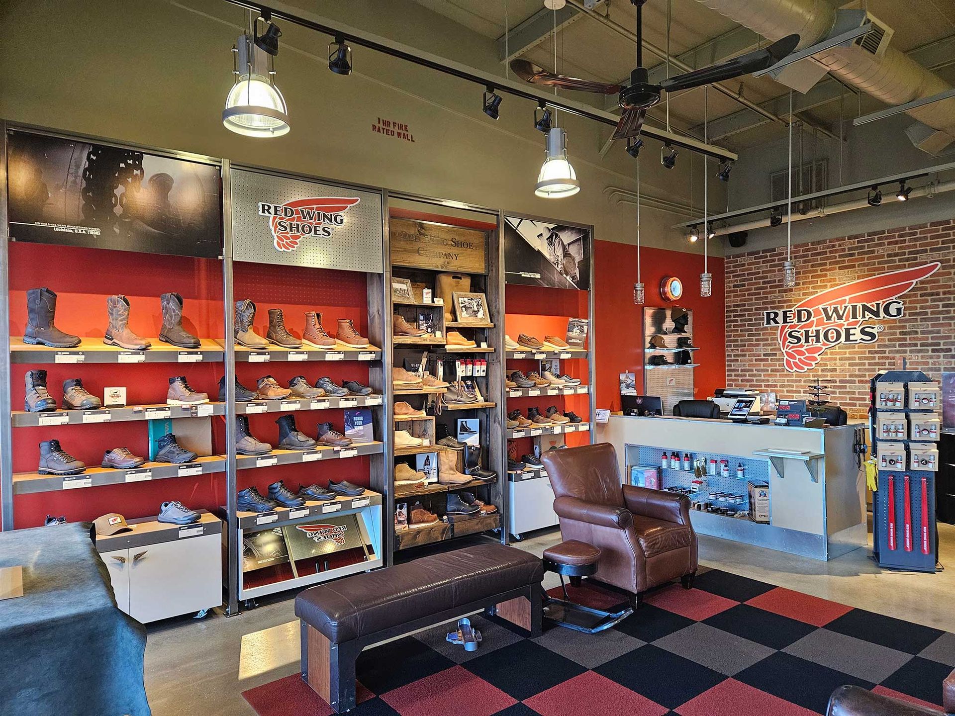 Interior of a Red Wing Shoes store with work boots on shelves, a seating area, and a checkout counter.